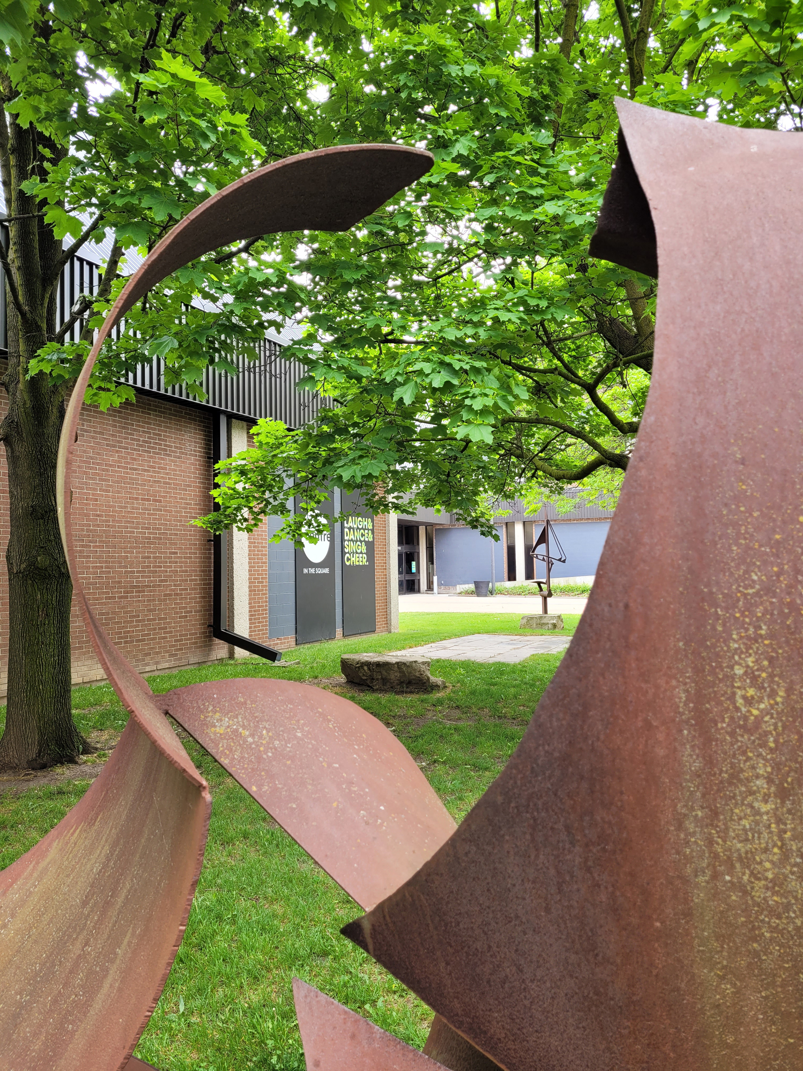 Close-up view through a corten steel abstract sculpture with Centre in the Square in the background