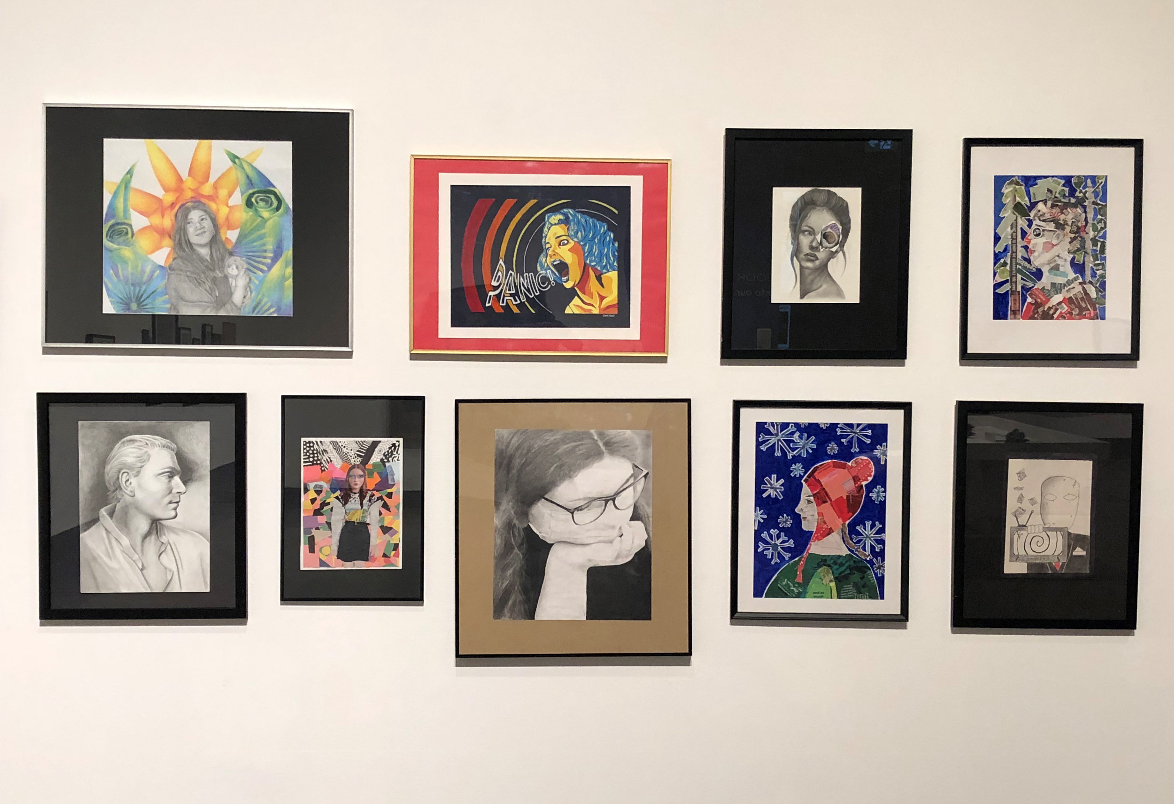 Installation view of a series of nine framed portrait works by students showing a range of styles, arranged in two horizontal rows on a white wall