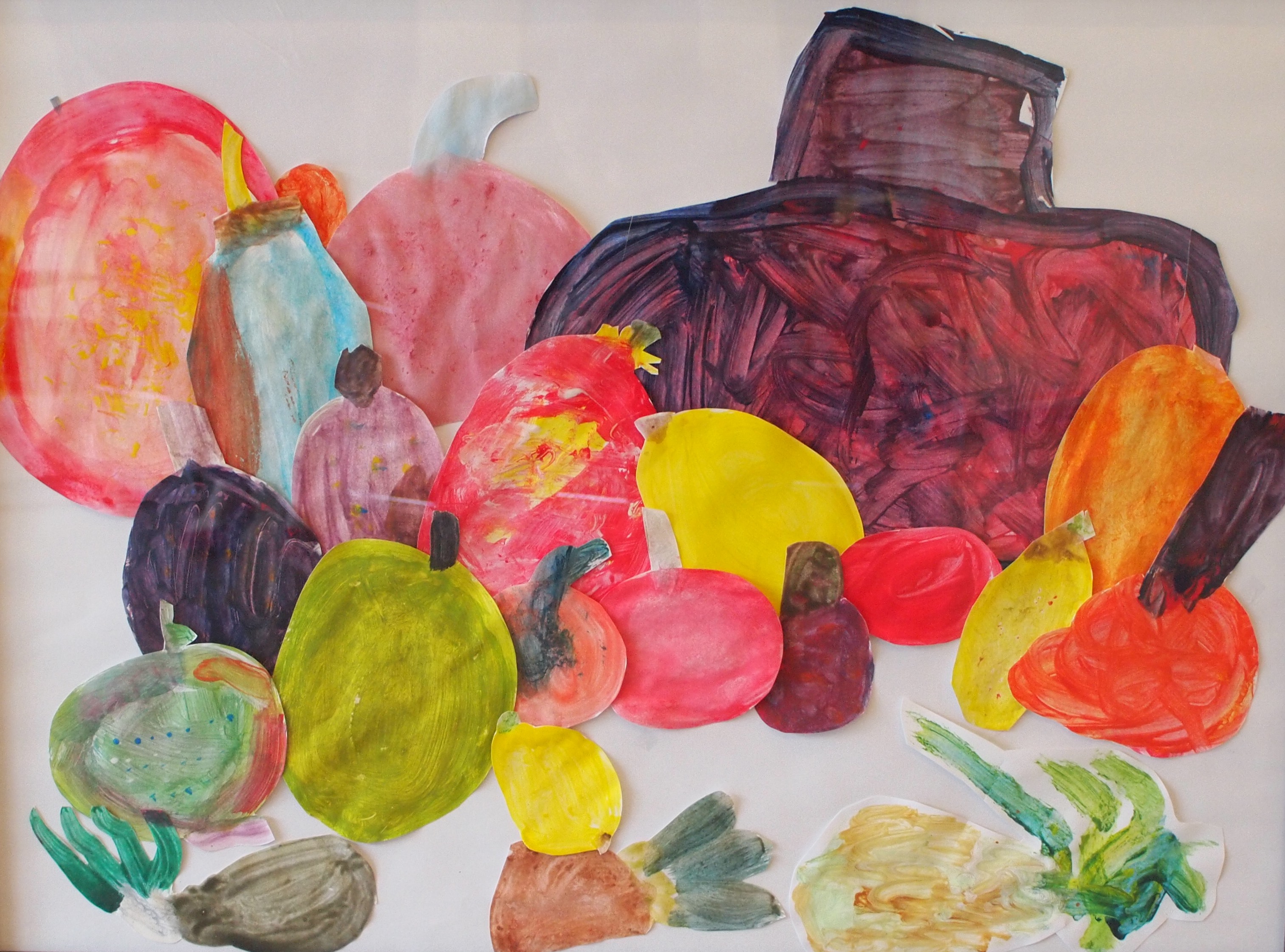 Fruit Bowl, a collaborative collage by Grades 1-2 students featuring cut-out shapes of painted fruit assembled together on a white background