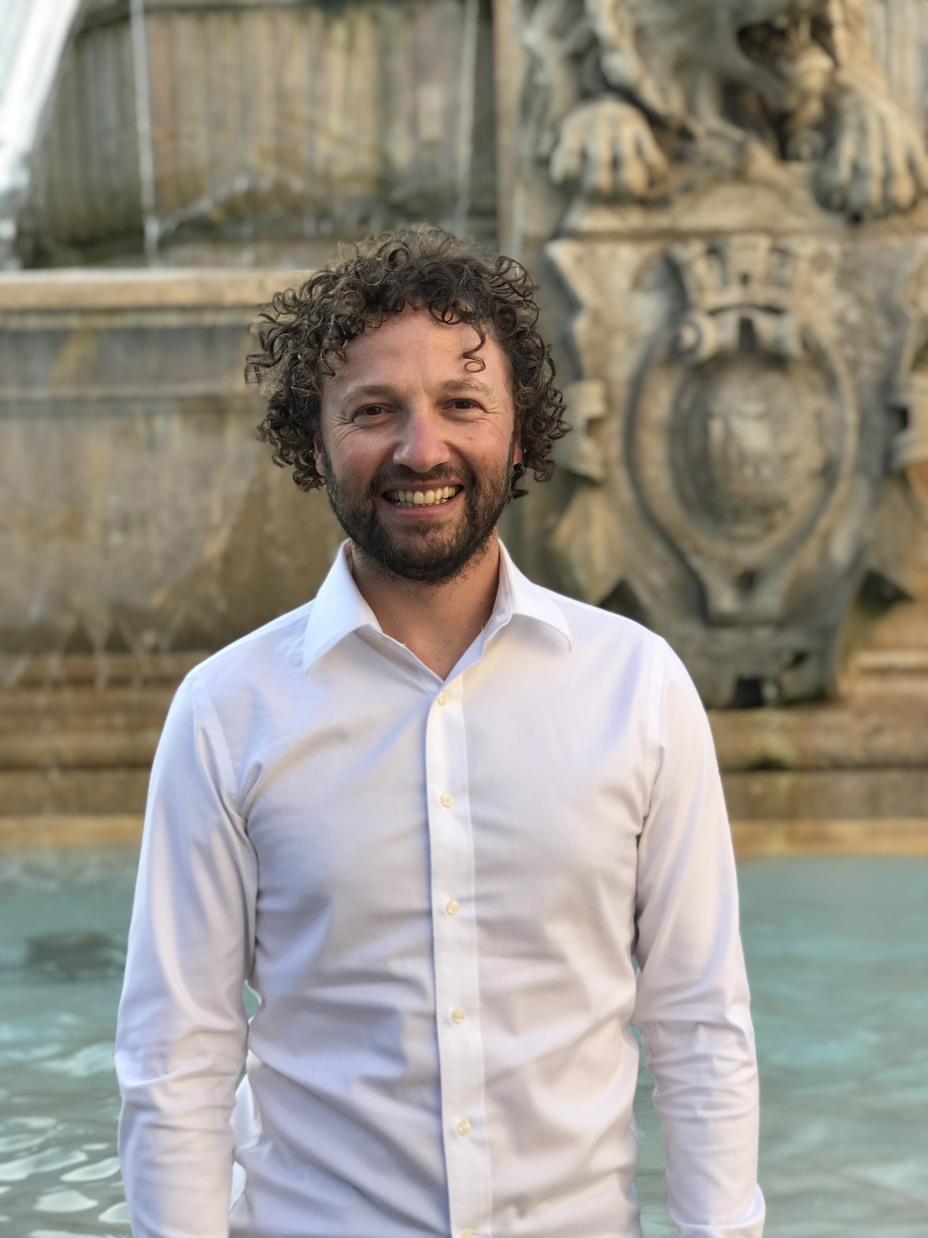 Photo of Adad Hannah, a smiling man with curly dark hair and a beard