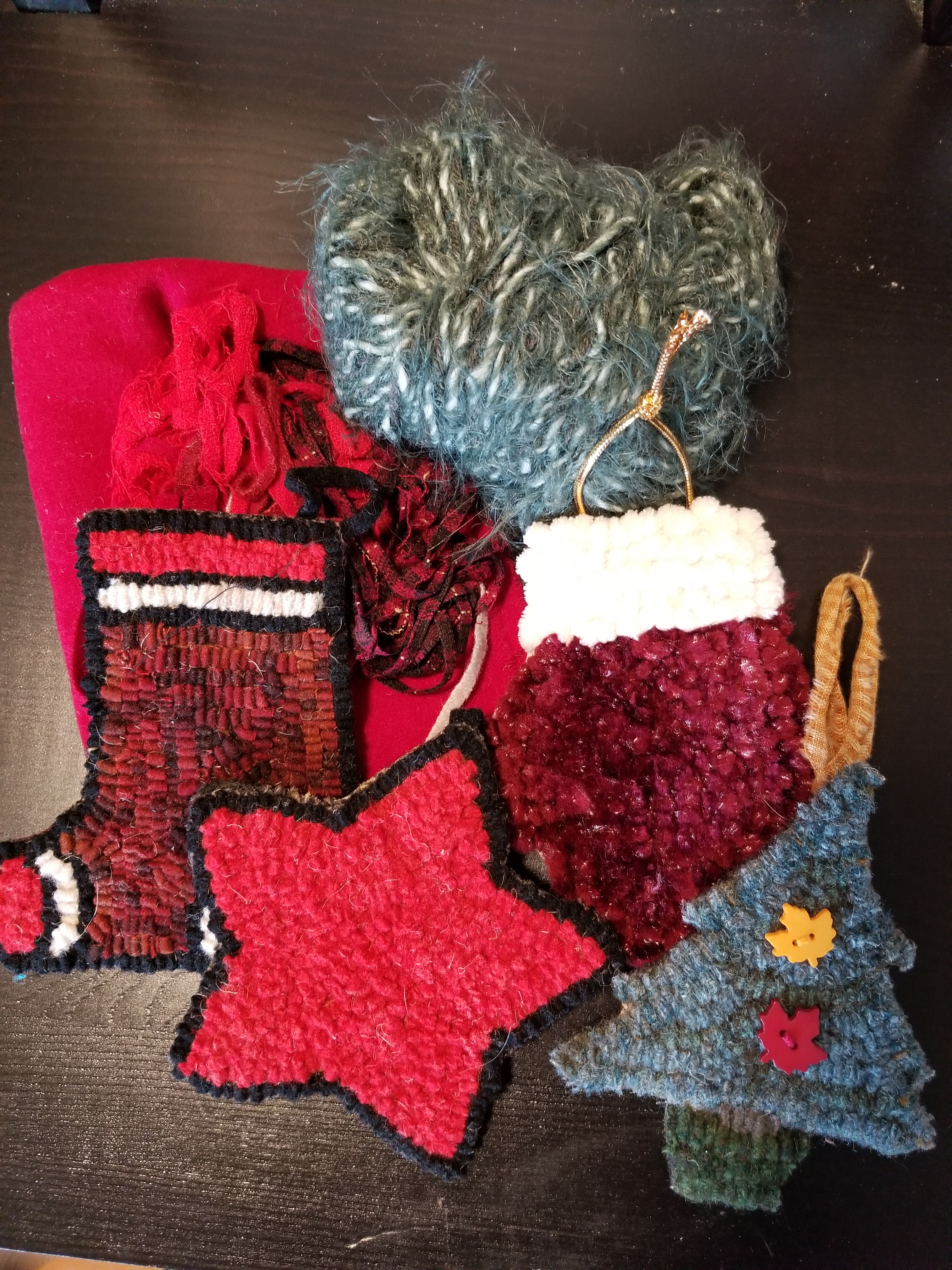 An array of rug-hooked holiday ornaments displayed beneath a ball of blue wool