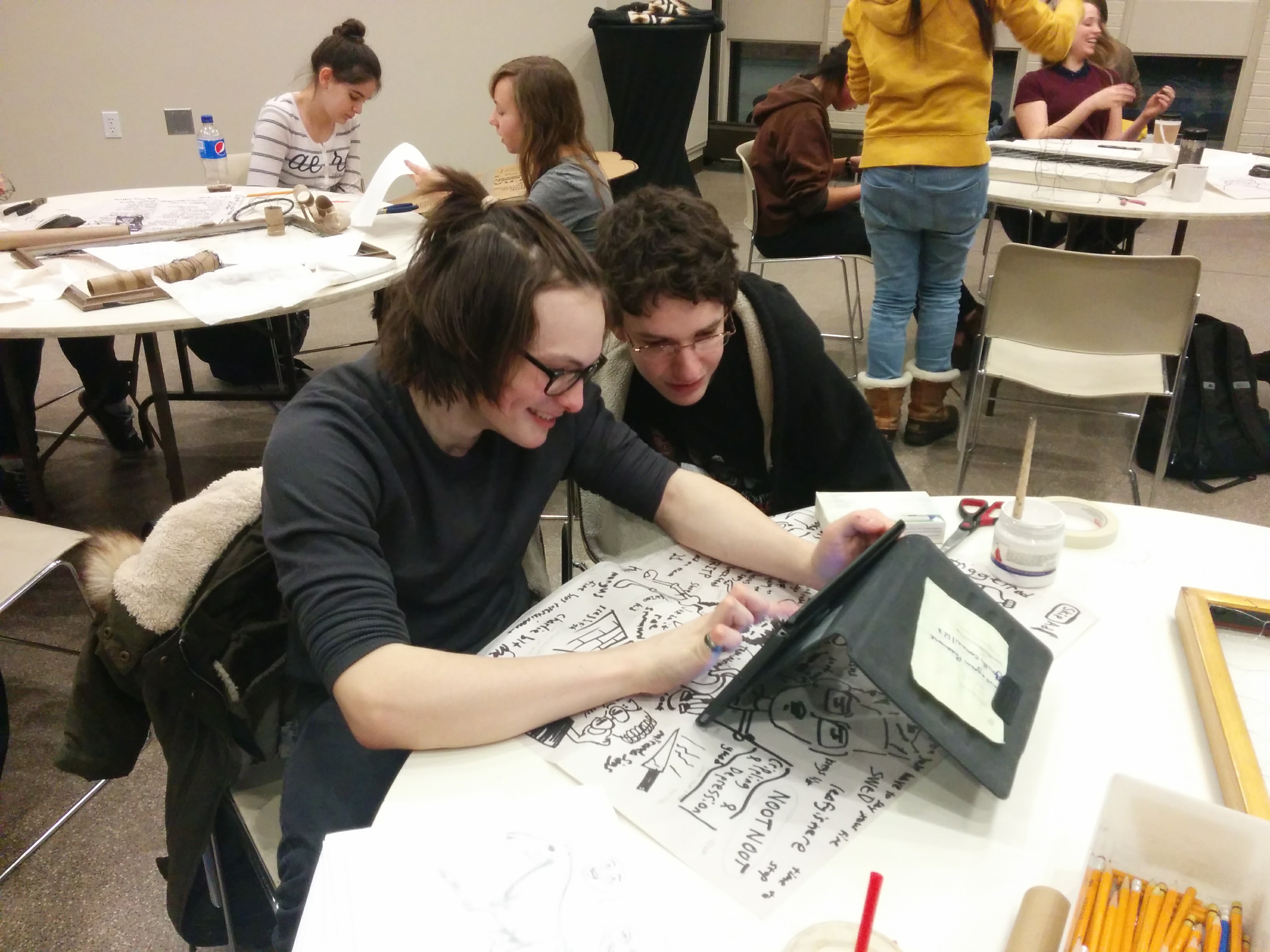 Two teenagers working together on an art project using an iPad at a Youth Council meeting