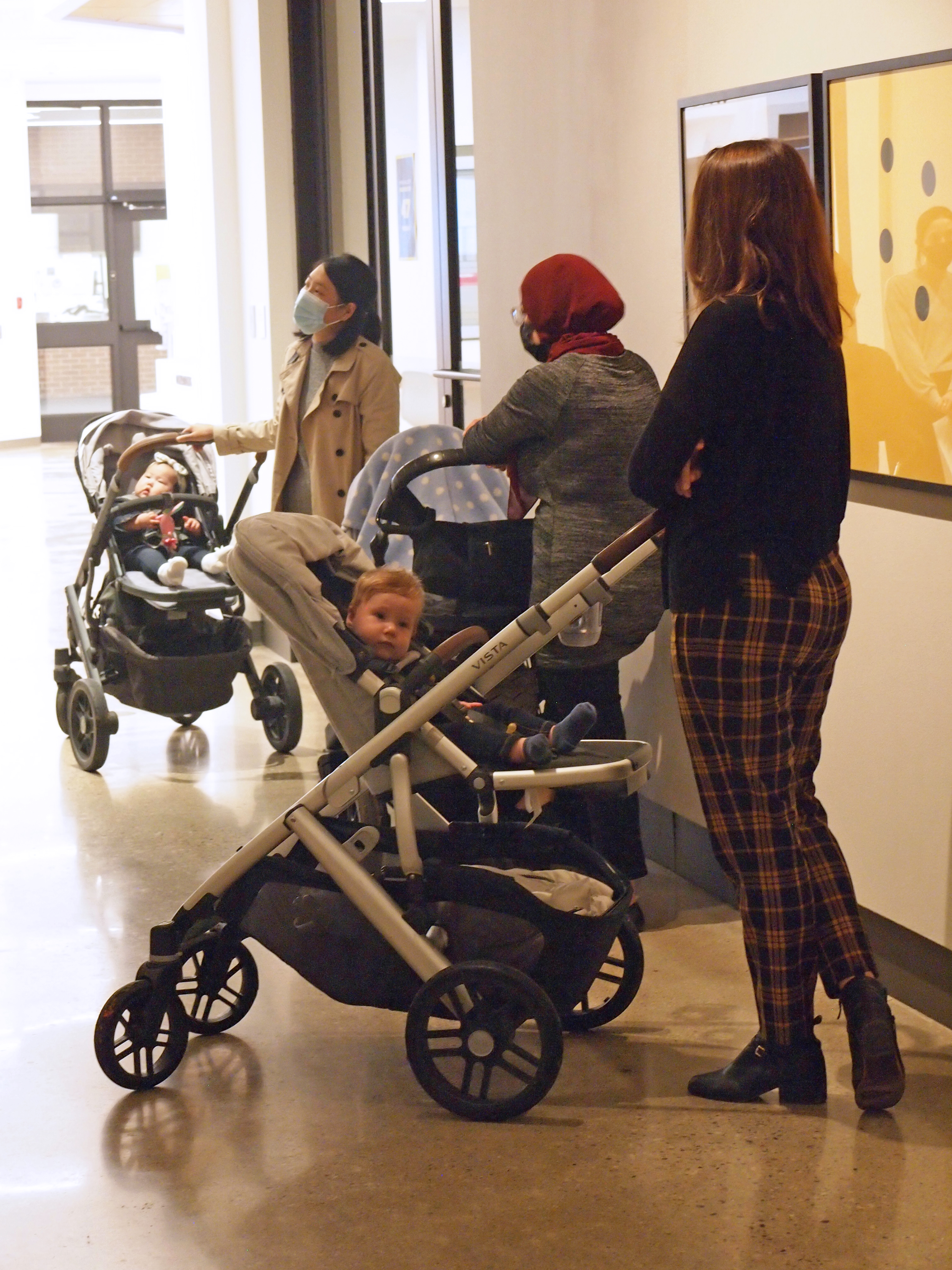 Three mothers with strollers stand in a row along the Corridor Gallery