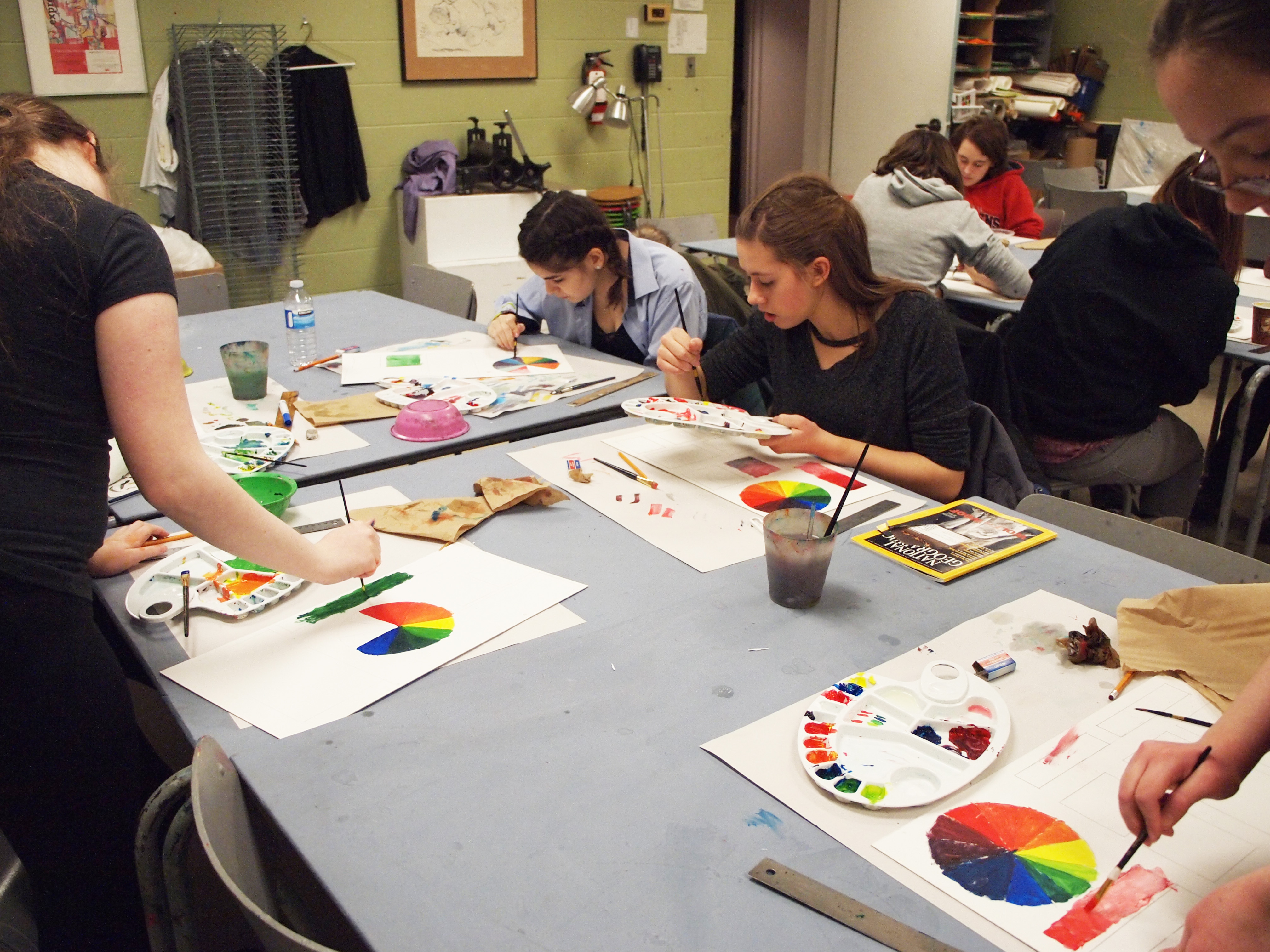 Youth Council members seated at studio tables practicing colour-mixing in acrylic paint