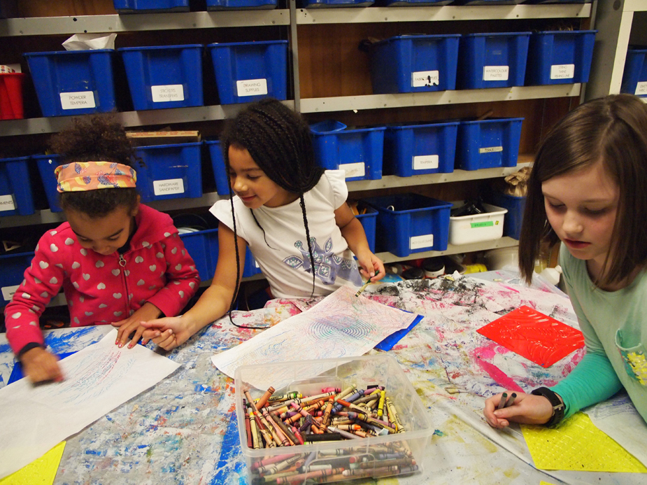 A group of three young girls creating colourful drawings in the KWAG studio