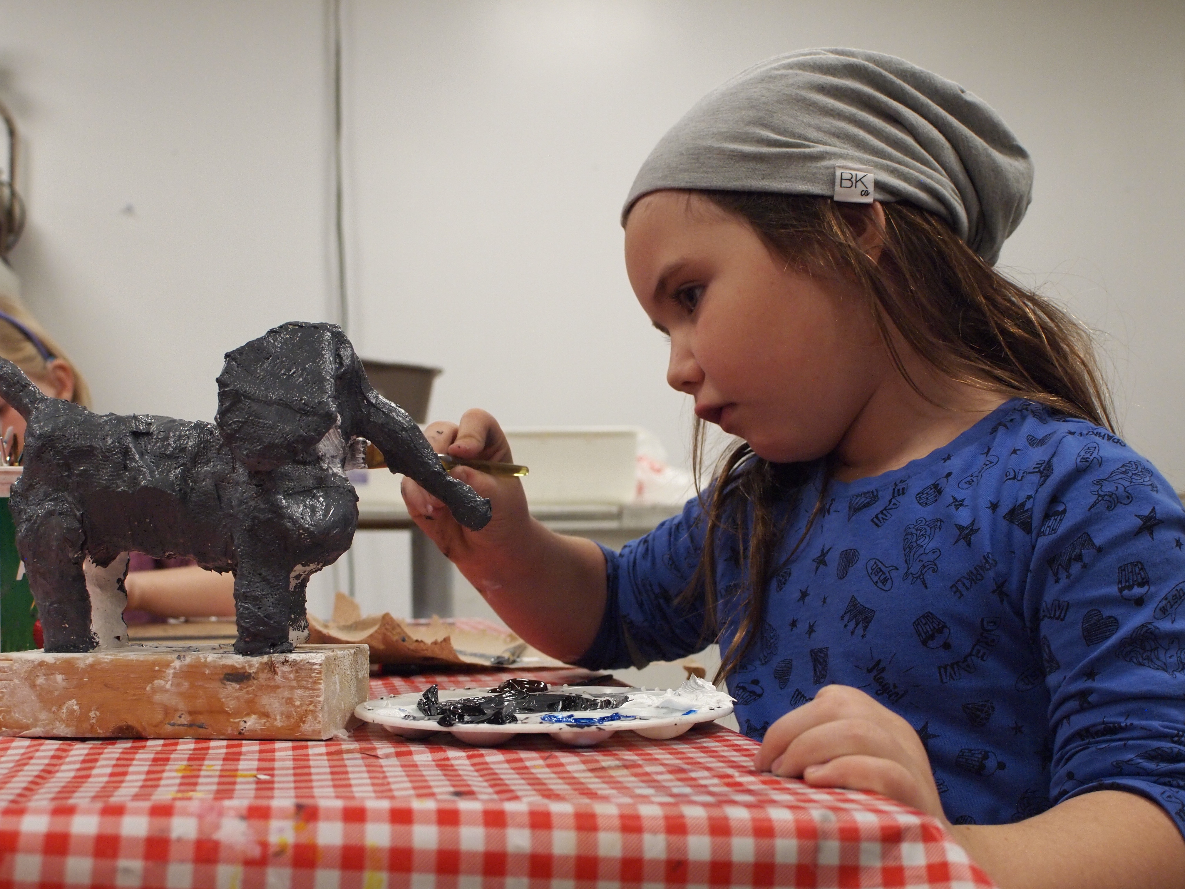 Profile photograph of a child painting a sculpture.