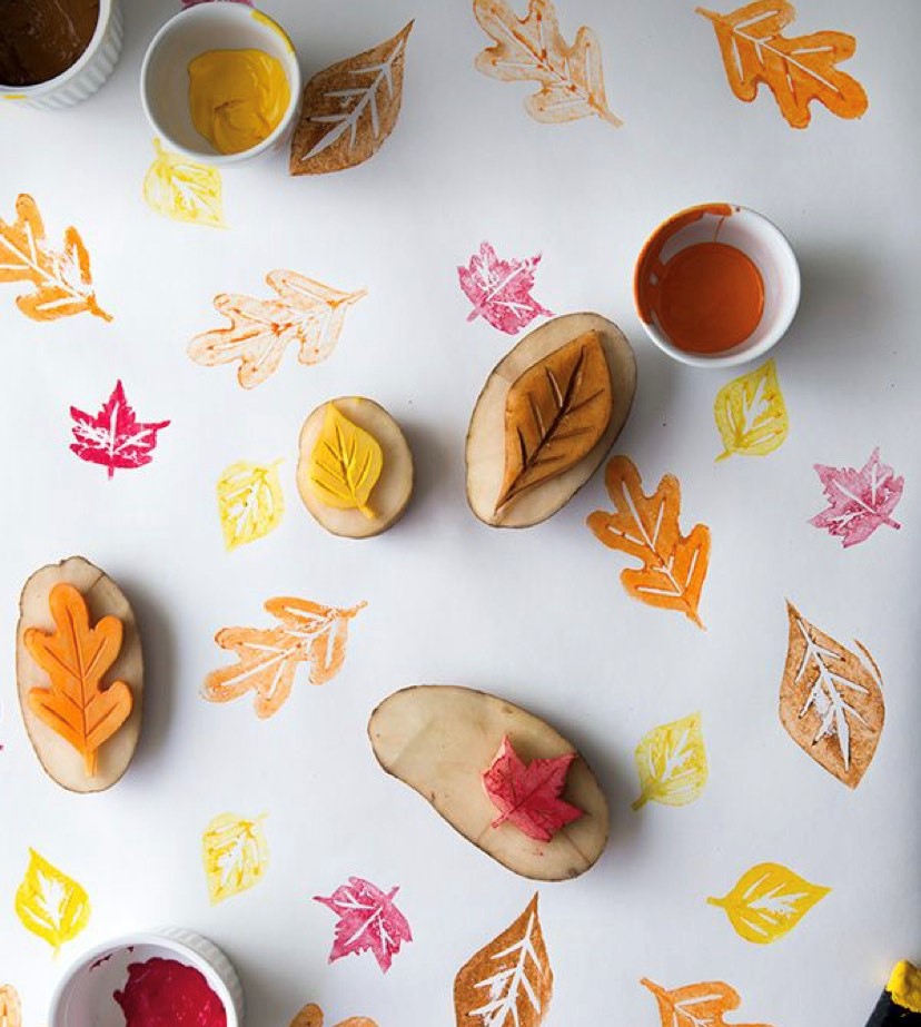 Overhead view of potato prints of autumn leaves stamped in shades of orange, yellow and brown ink