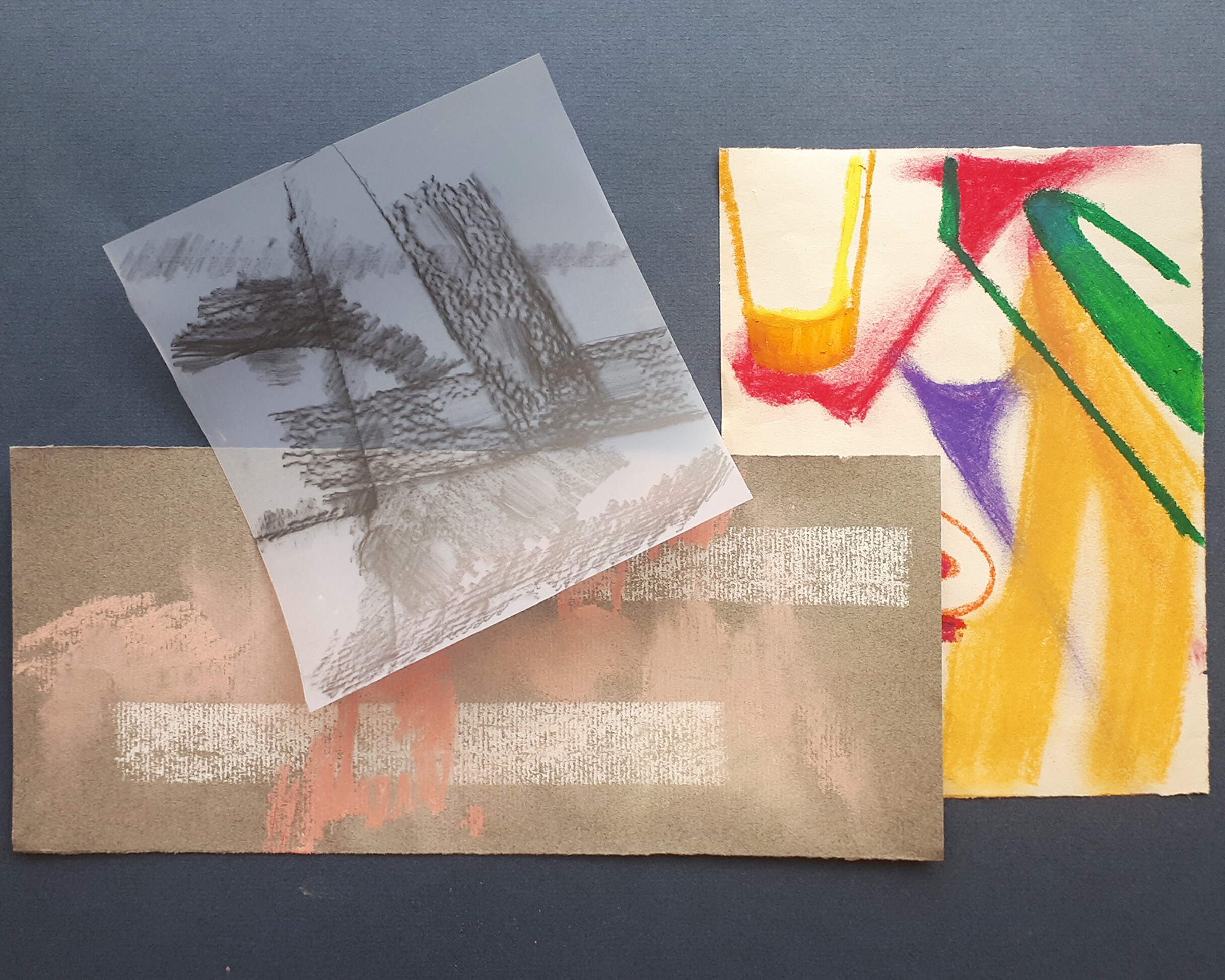 A set of three drawings on paper and vellum arranged on a dark grey table surface