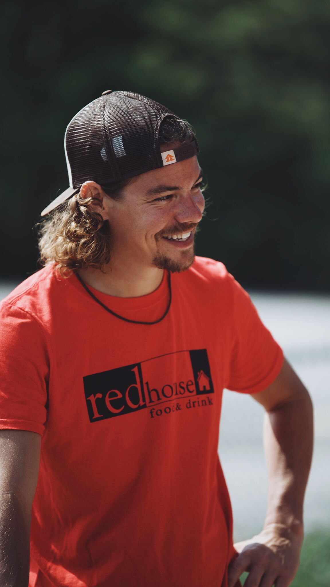Photo of Chef Dan McGowan, a young man with longer brown hair in a baseball cap and Red House t-shirt