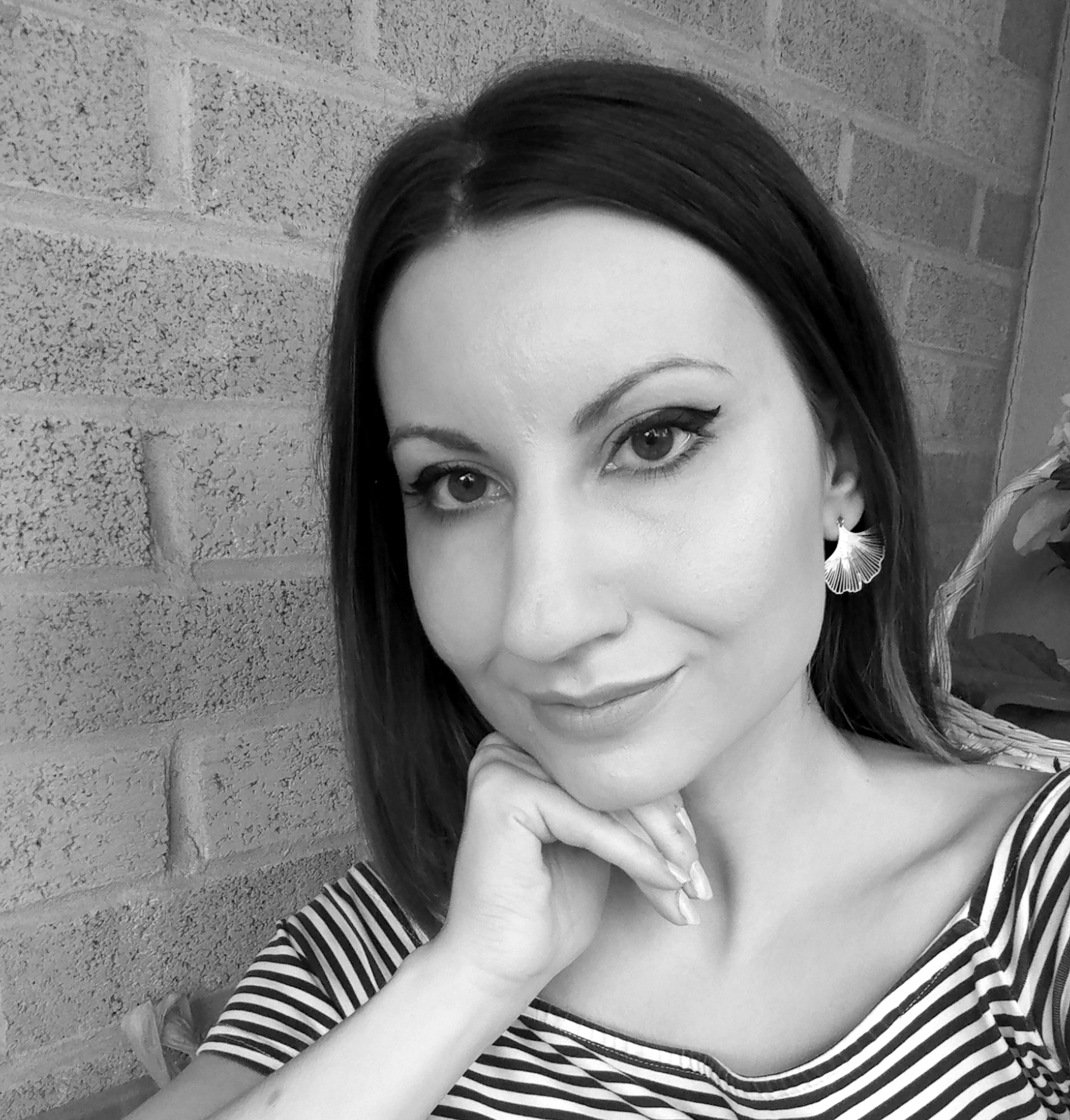 Black and white photo of Žana Kozomora, a young light-skinned woman with long dark hair resting her chin on her hand, wearing a striped top