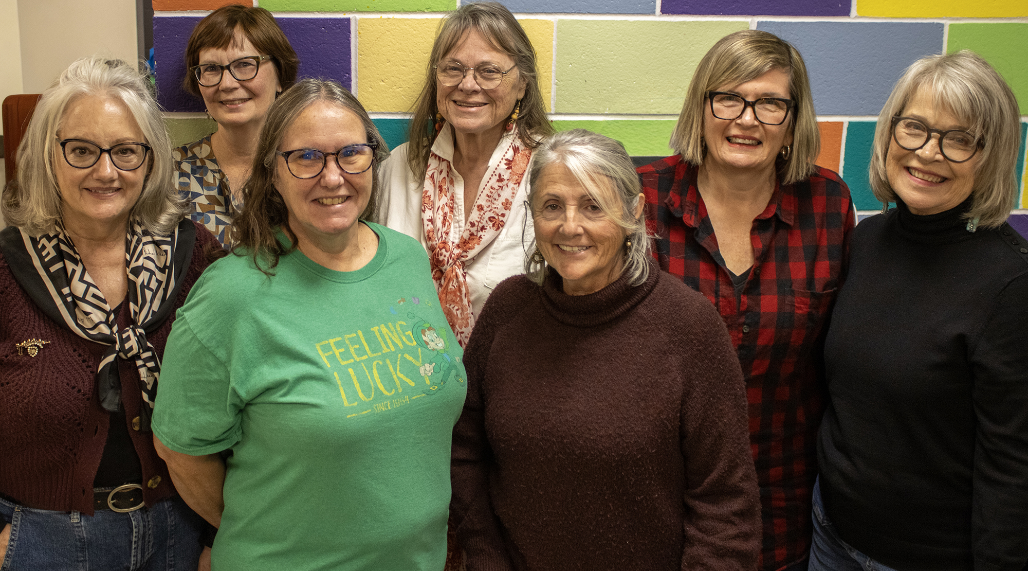 Group photo of smiling volunteers set against a colorful back drop