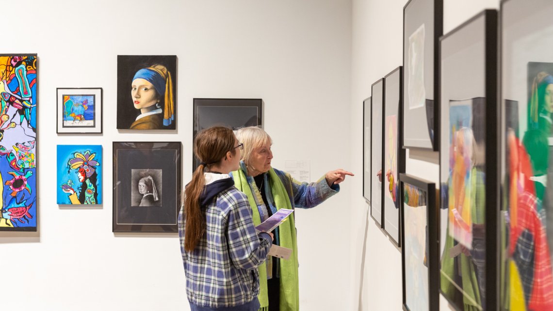 Side view of two people interacting with a framed piece of art in the main gallery
