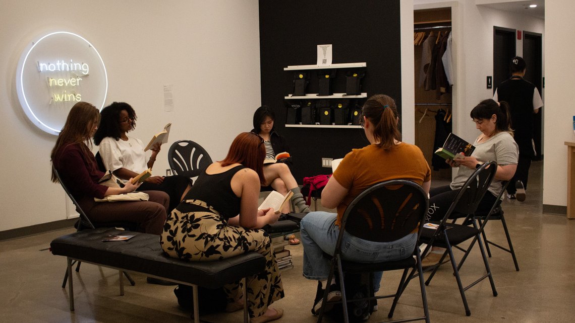 Photo of a group of people sitting on chairs in a circle reading books