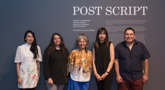 Susan Blight, Lisa Myers, Mary Anne Caibaiosai, Melissa General and Luke Parnell stand together in front of the title wall for Post Script