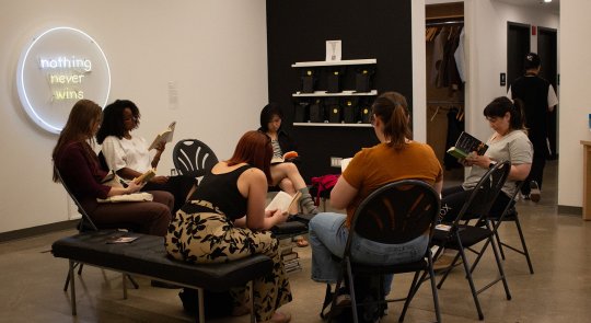 Photo of a group of people sitting on chairs in a circle reading books