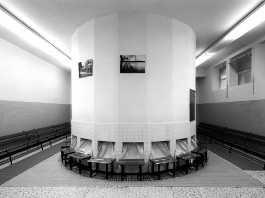 A black and white Lynne Cohen photograph of a tiled spa interior dominated by a round white structure that fills the low-ceilinged space