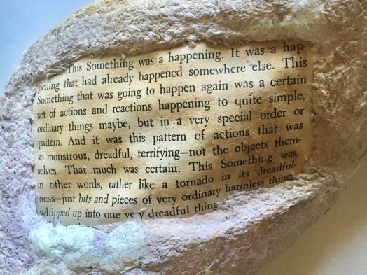Close up image of a rock formation made from paper pulp embedded with a legible page of text from a yellowed trade paperback book