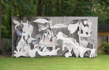 Adad Hannah photo of a restaging of Picasso's Guernica using wood and cardboard cut-outs, arranged in a lush green backyard space