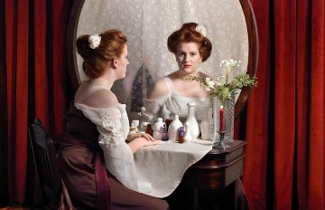 painted portrait of a woman dressed in a red and white dress sitting in front of a vanity mirror.