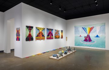 Full view of the gallery containing a selection of volcano, skull-shaped and globe-like ceramics with the background of tufted wool volcano wall hangings