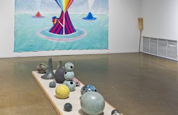 Large painted canvas of a volcano spuing a rainbow and ceramic volcano pottery underneath