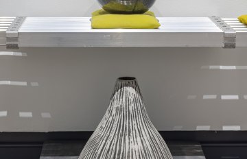 Globe-like ceramic sitting on a shelf with another ceramic volcano on a plinth on a floor