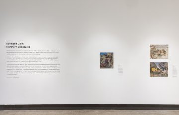 Installation view of a white wall with vinyl lettering and three landscape paintings