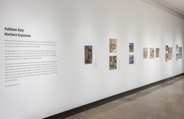 Side view of a white wall with numerous landscape paintings