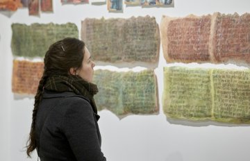 image of gallery exhibition with walls covered in writing with a person admiring the artwork