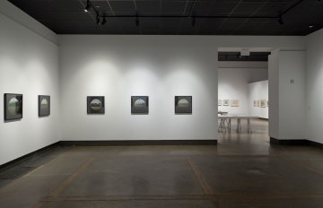 exhibition installation shot of pictures hanging on the wall and doorway leading into the next room showing