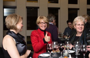 Three women with standing around a table of wine glasses