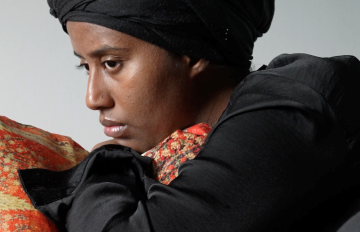 black woman with a melancholy look on her face laying on furniture