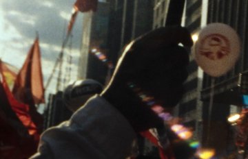 photo of hands reaching towards the sky with a solar flare and city buildings in the background