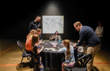 Several people around a table playig what appears to be a card game