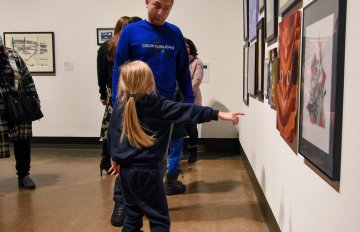 a family admiring the artwork hung on the wall