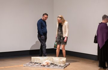 large stone artwork on floor being admired by man and woman