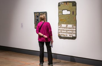 Large artwork resembling a cellphone hung on wall being admired by a woman