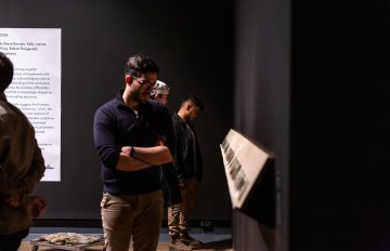 artwork laid out on a shelf being admired by a man in the gallery