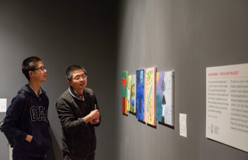 people admiring the artwork on the wall of the exhibition