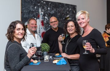 Group photo of people holding wine glasses smiling at the camera 