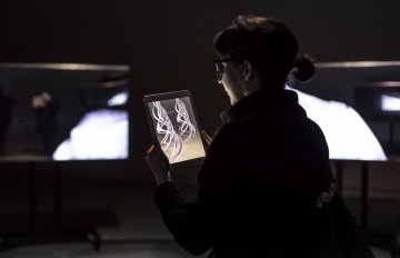 person looking at two tv screens playing imagery across them