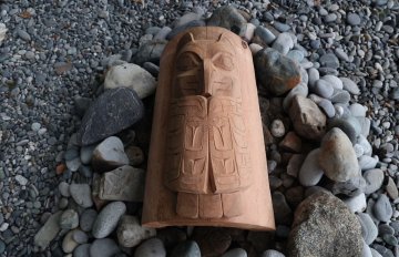 a totem pole laying on the ground with rocks around it