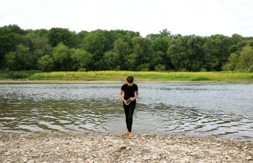a person walking out of the water facing the camera, but looking downwards.