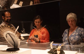 People gazing through glass at sculptures made of bone, feather and mineral rock