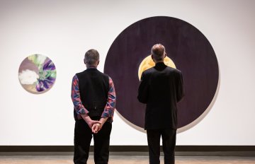 two people admiring circular artwork hung on the wall