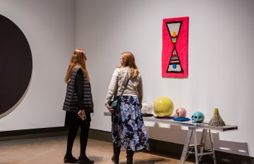 two people looking at raku pottery on display