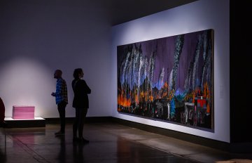 large abstract painting hun on wall looked at by two people