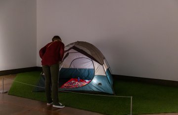 a tent set up in the gallery being looked at by a gallery visitor