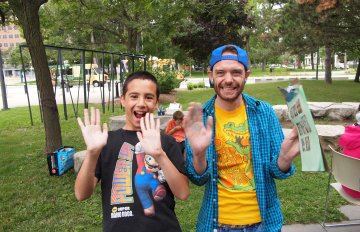 Two young people smiling and holding their hand up outside on the KWAG lawn