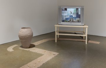 Unfired clay vessel on a cob pattern with a tv in the background